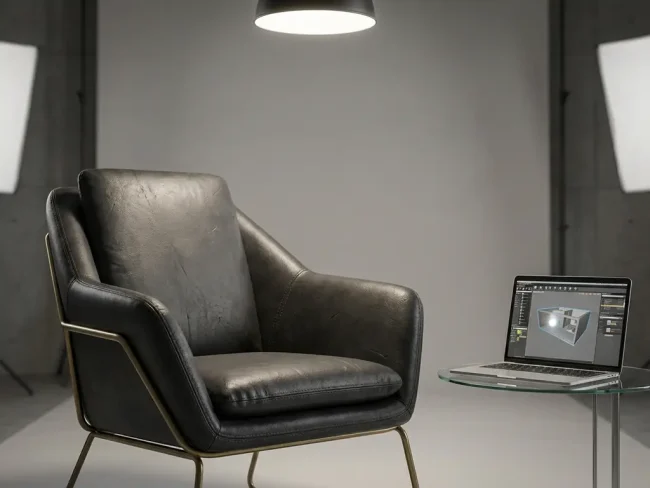 Modern leather armchair with metallic accents in minimalist studio with laptop showing 3D modeling software on glass table